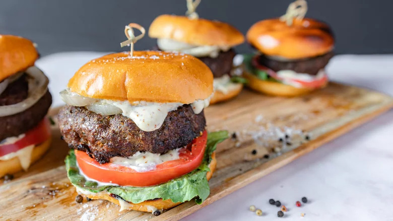 Burgers with creamy sauce on board