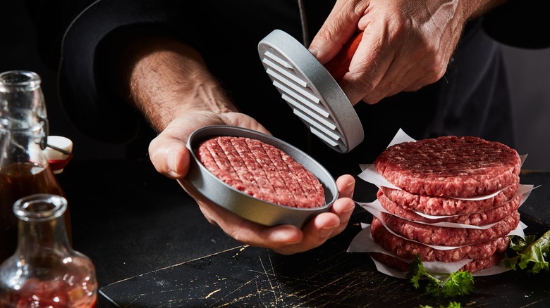 chef making fresh burger patties with a press