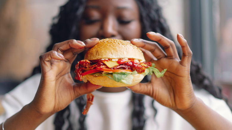 person holding a burger with different toppings