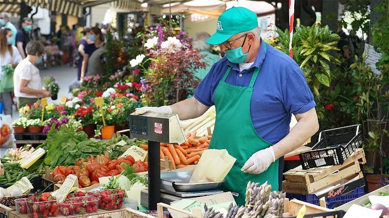 masked man weighing produce