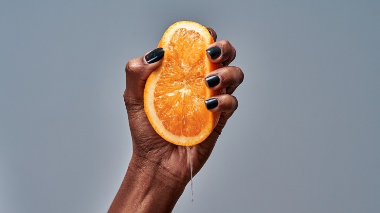hand squeezing cut orange 