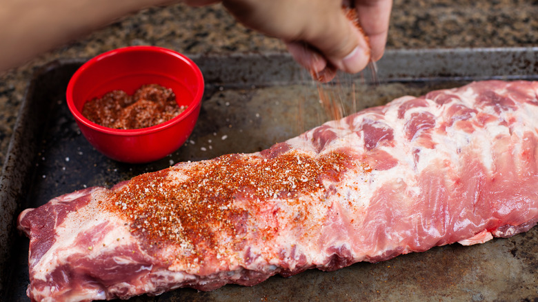 Hand sprinkling spices on ribs