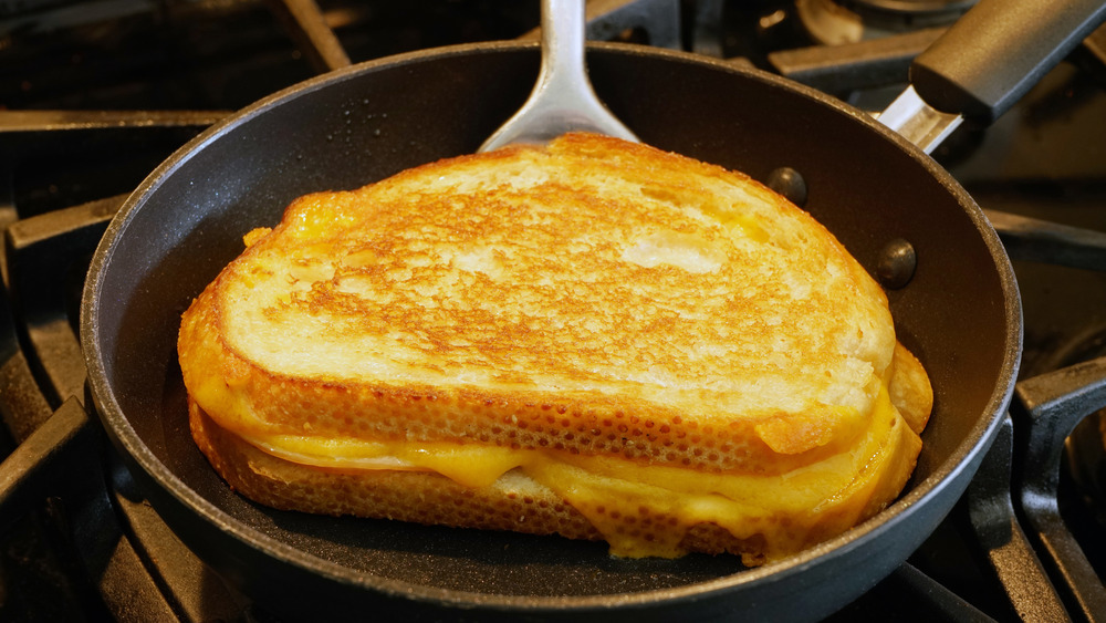 spatula and pan with grilled cheese on top of stove