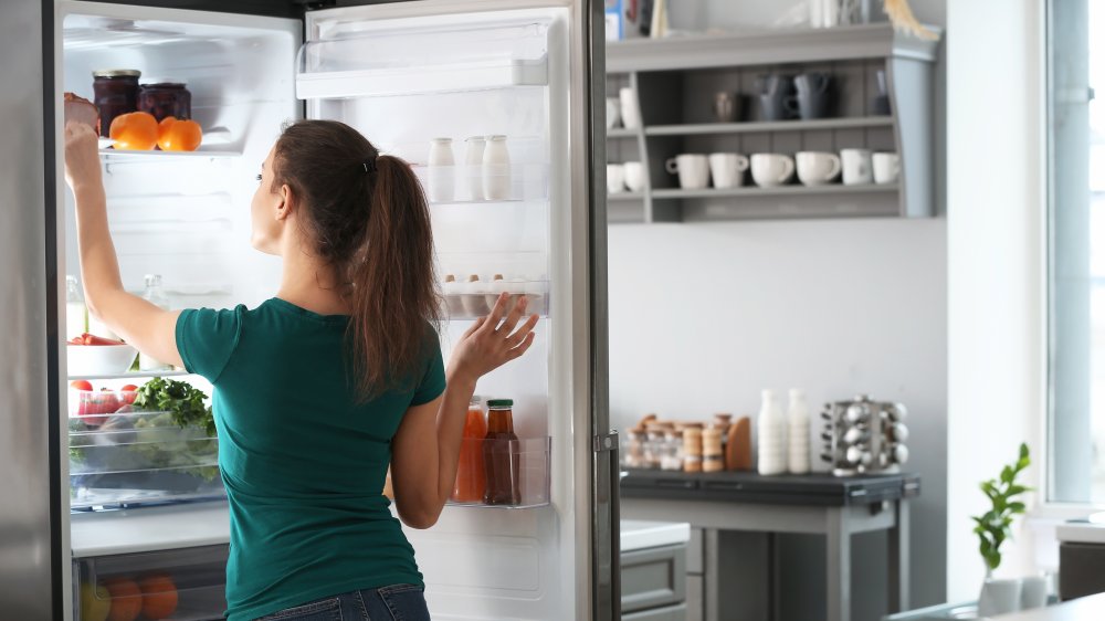 woman looking in fridge at potato salad