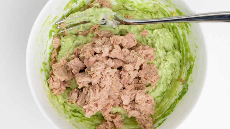 bowl of mashed avocado with chunks of tuna fish