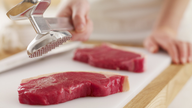 Steaks below a meat mallet