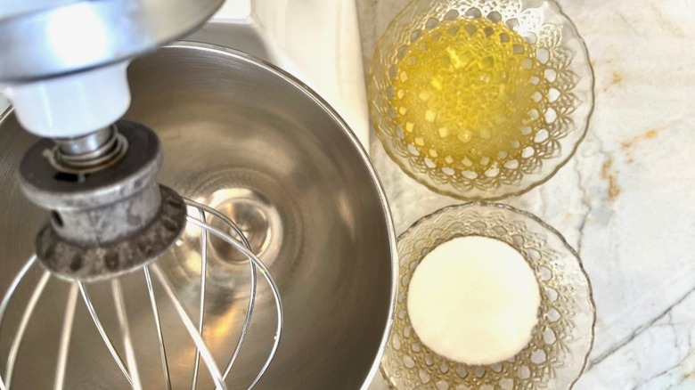 Close up of an electric mixer next to two glass bowls of ingredients