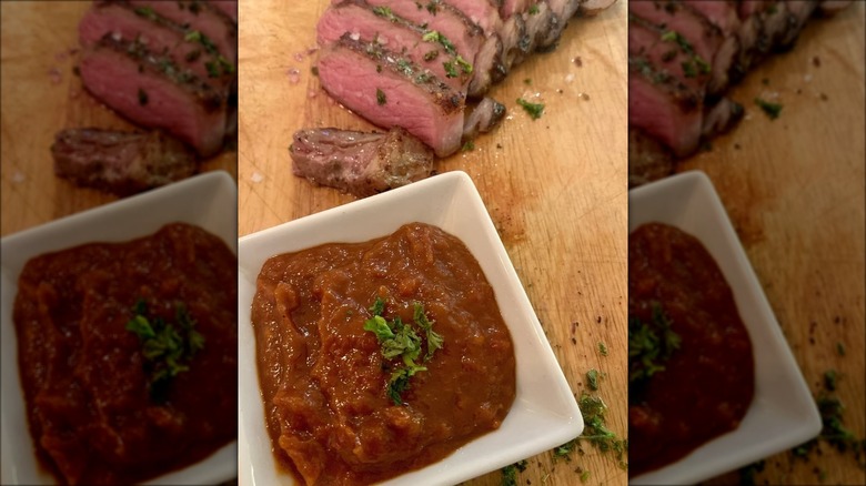 A bowl of monkey gland sauce and sliced steak.