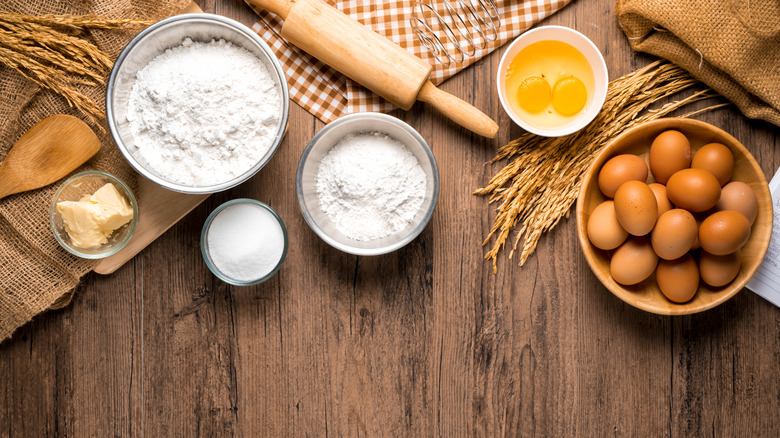 Flour, eggs, and rolling pin on wood table