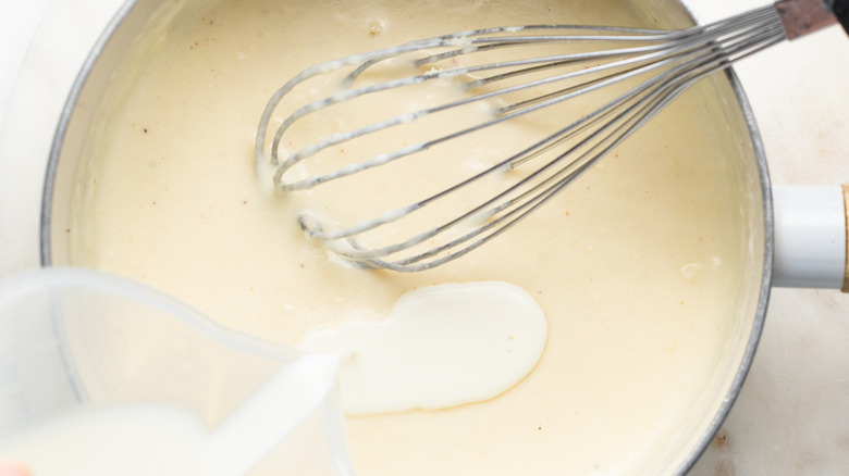 pouring milk into white sauce