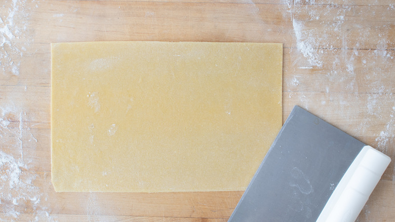 rolled out pasta dough on wood board