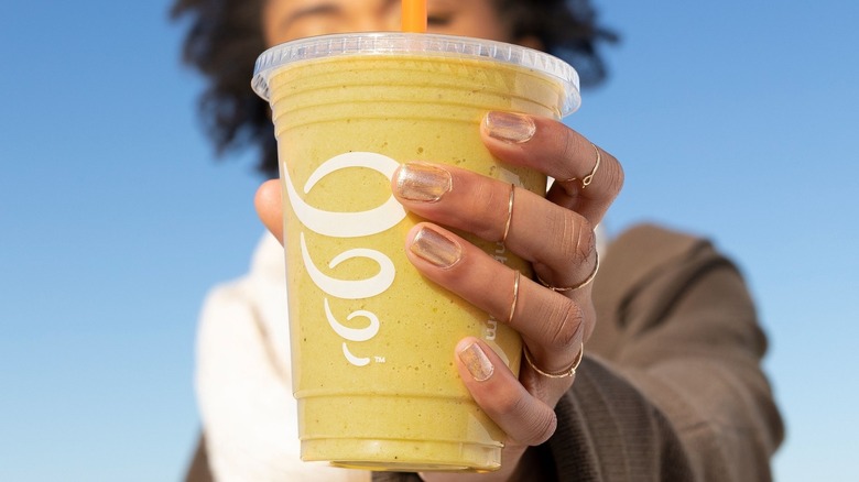 Person's hand with gold nail polish holding mango Jamba smoothie