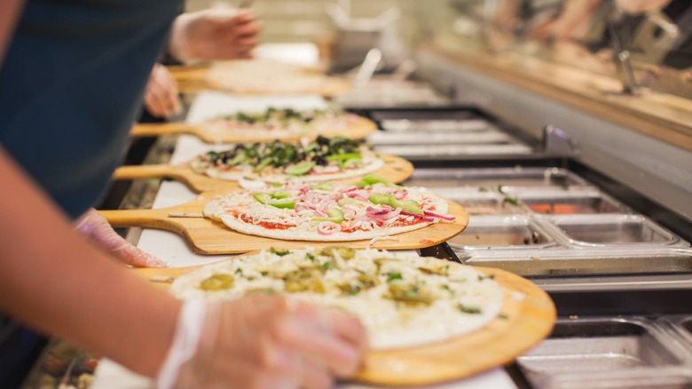 Line cooks prepping Pieology pizzas