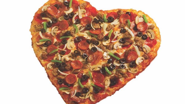 Heart-shaped pizza with pepperoni and veggies on white background