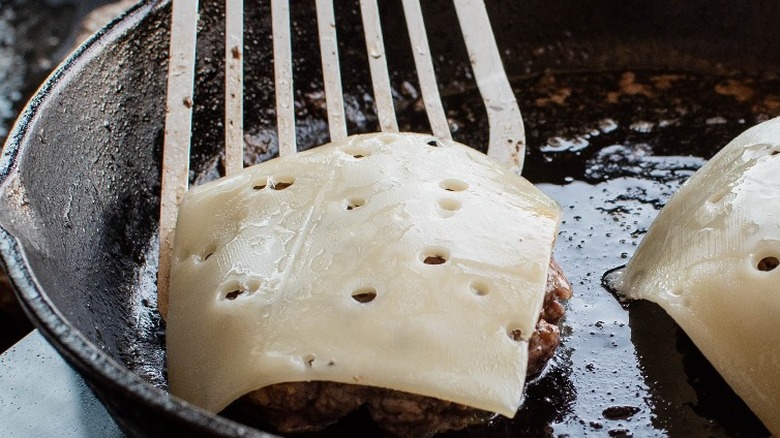 Hamburger in skillet with swiss cheese on top