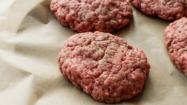 ground beef shaped into ovals on parchment