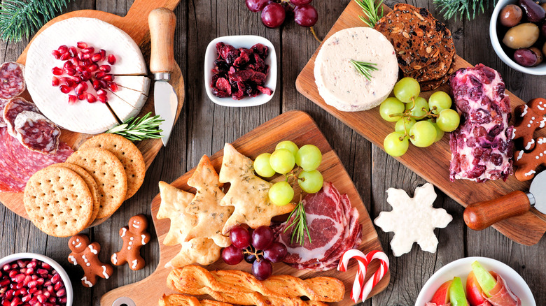 small wooden boards with assorted charcuterie including Christmas tree shaped crackers and gingerbread men cookies