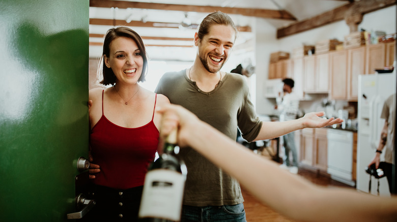 handing wine to couple