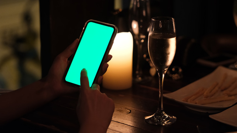 smartphone and wine glass at table