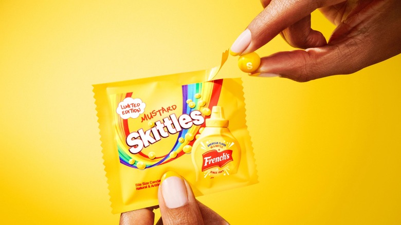 hand taking candy out of packet of French's mustard-flavored skittles