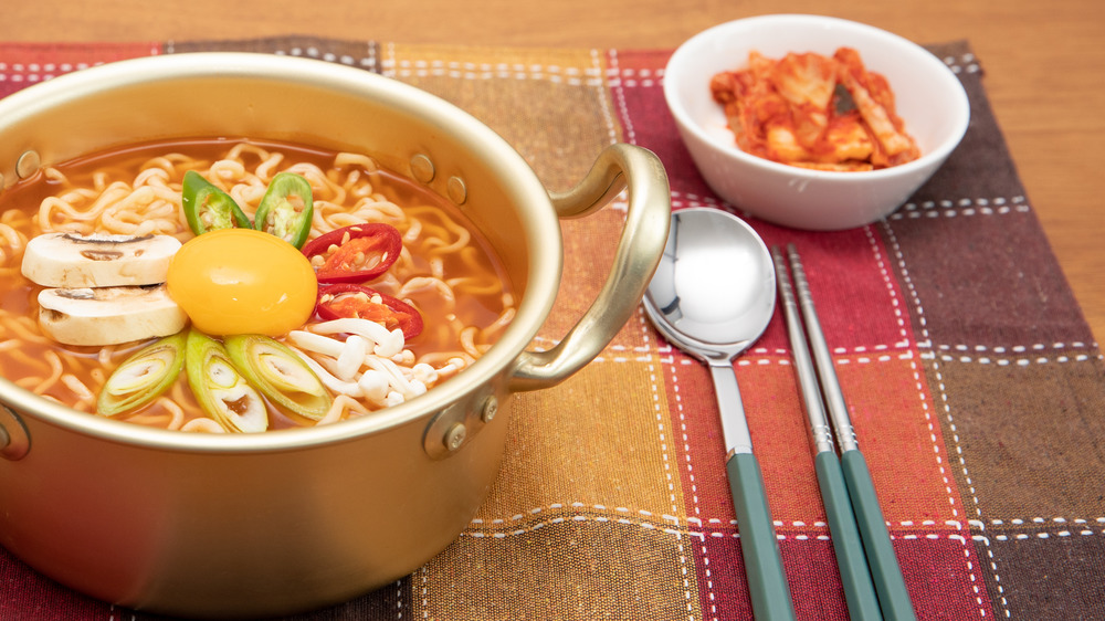 Soup with mushrooms and noodles in pot on cloth placemat