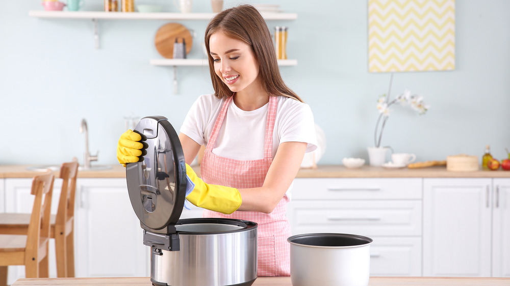 Woman wearing yellow gloves while cleaning a slow cooker