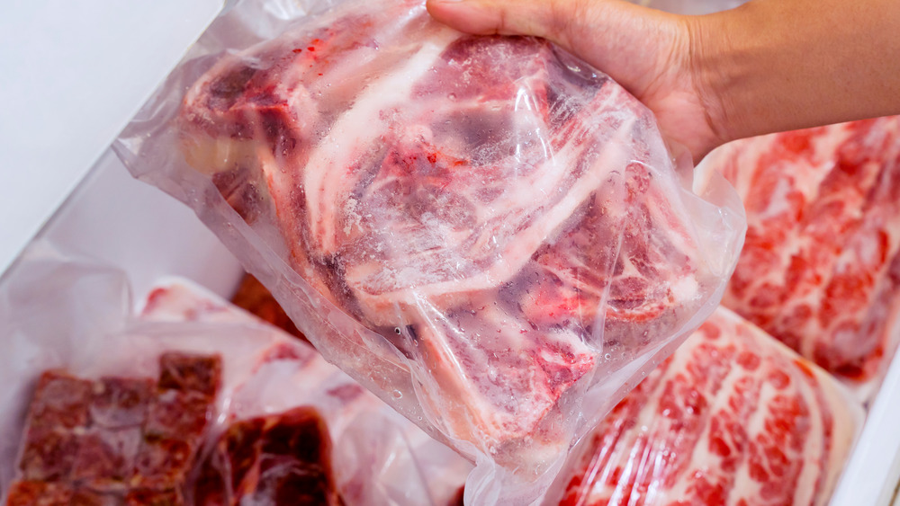 Hand holding plastic packaged frozen meat