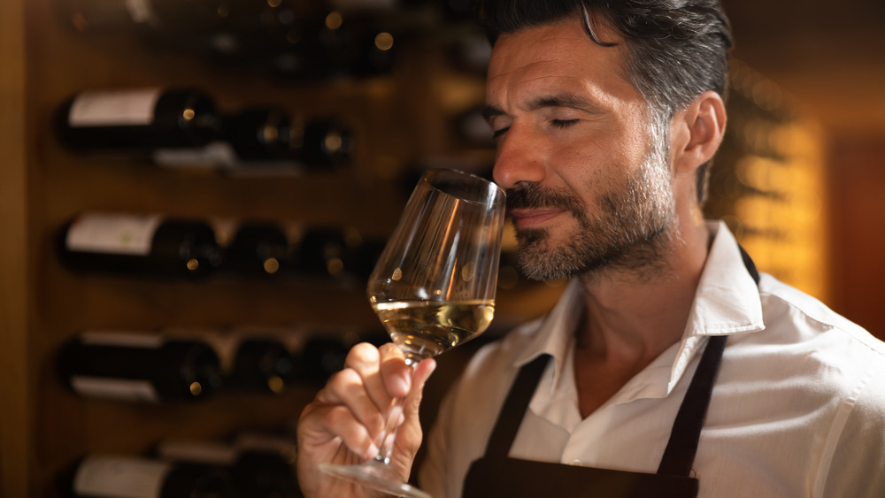 Sommelier smelling white wine in wine cellar
