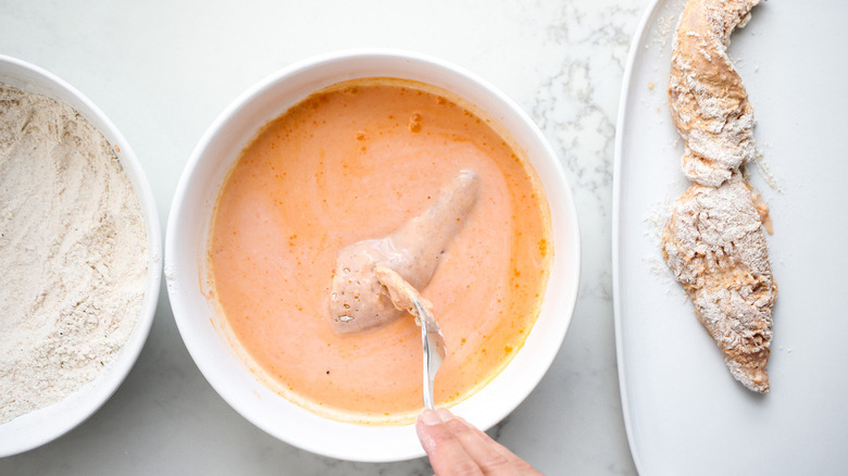 hand coating chicken in sauce