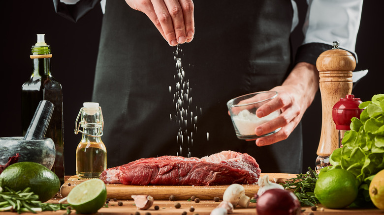 Person in black salting a steak