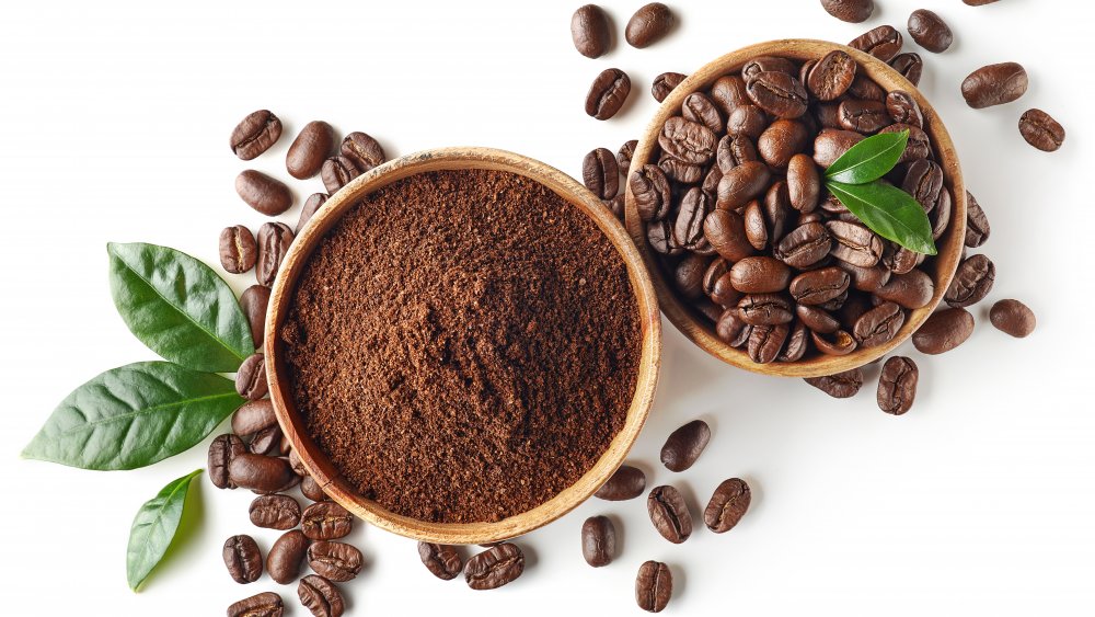 Whole and ground coffee beans in wooden bowls