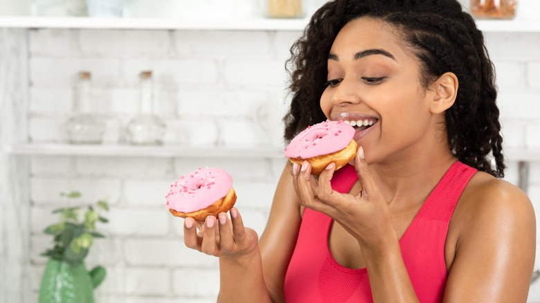 A woman eating doughnuts, one in each hand