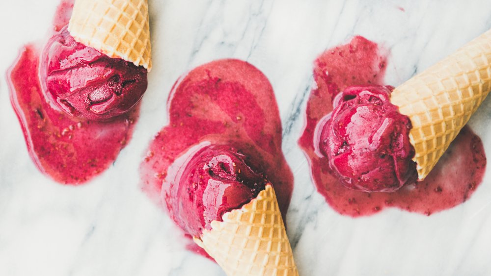 berry ice cream scoops melting on a marble countertop 