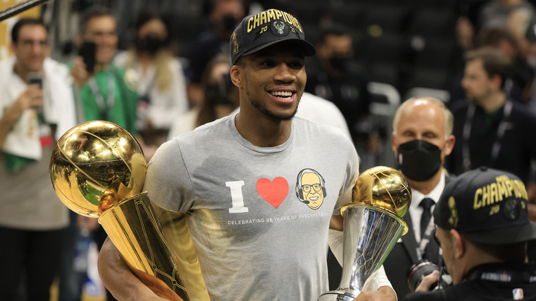 Giannis Antetokounmpo holding his two trophies