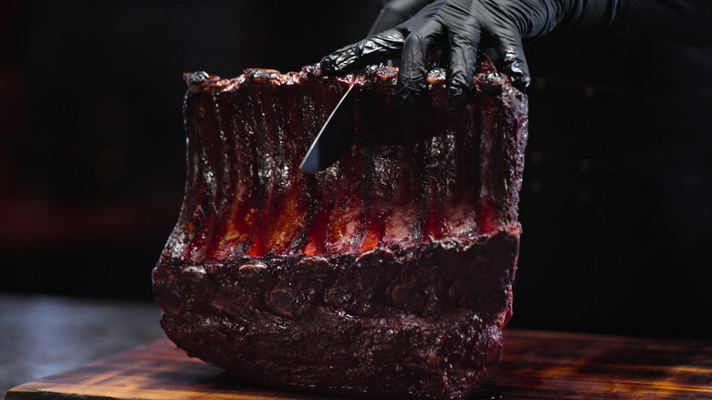 Gloved hand cutting BBQ meat