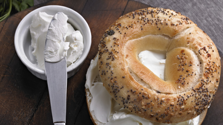 Everything bagel next to cream cheese with a knife