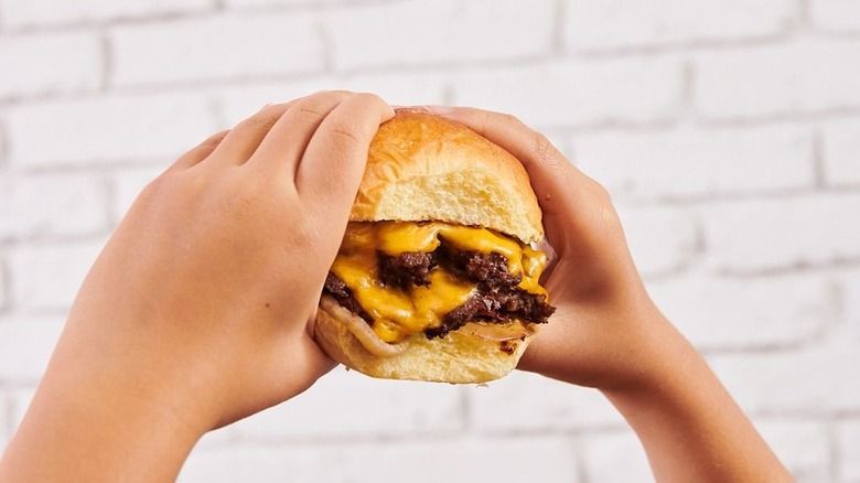 holding cheeseburger up fluffy bun