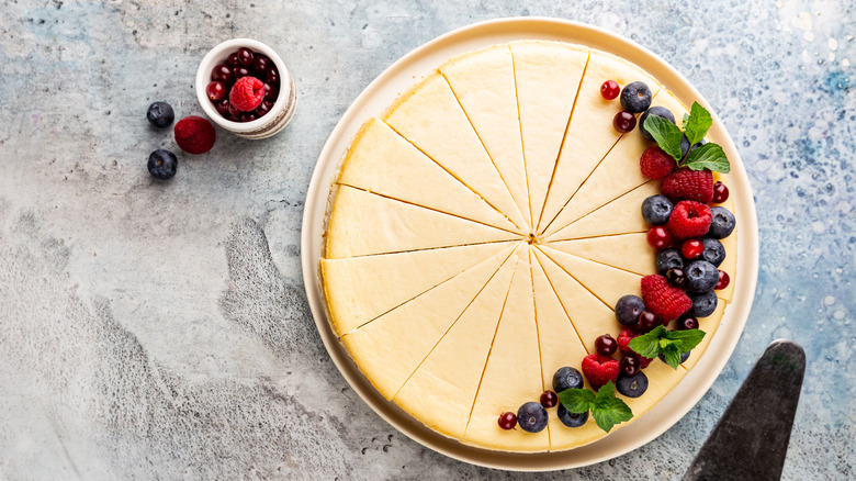 overhead picture of cheesecake, sliced and topped with berries