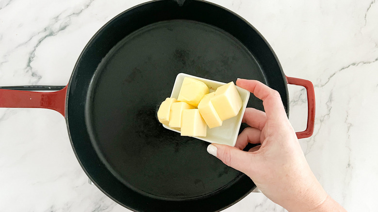 hand putting butter in pan