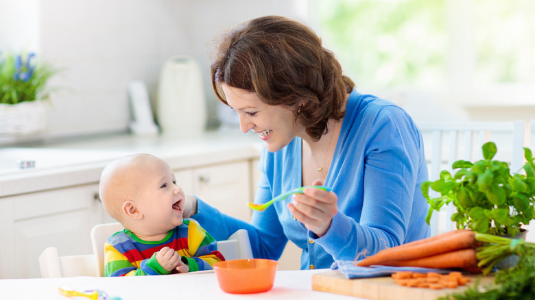 Mother feeding baby vegetables