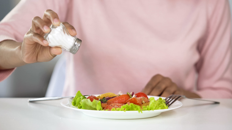 woman adding salt to meal