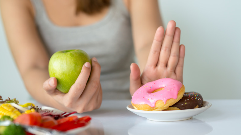 Woman choosing apple over doughnut