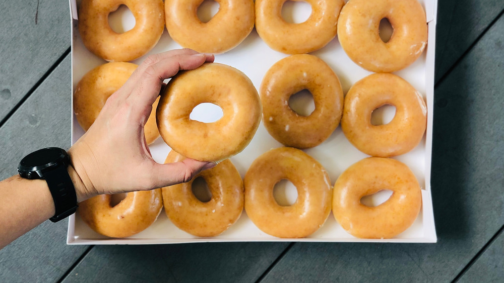 Hand grabs fresh glazed donut