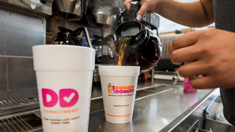 A Dunkin' employee pours coffee