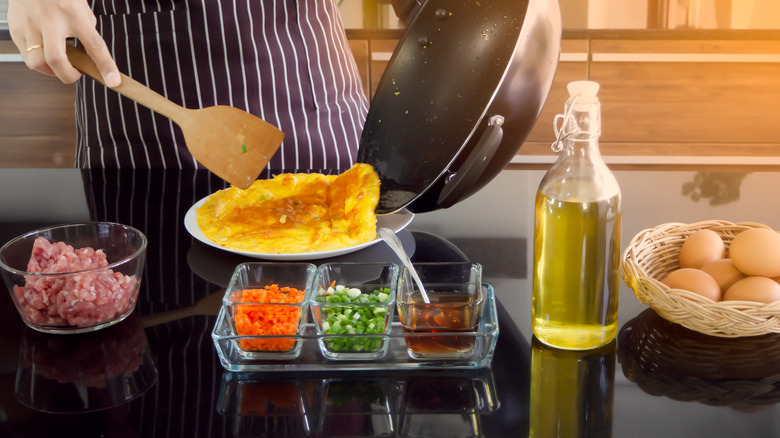 Person in black apron making an omelet