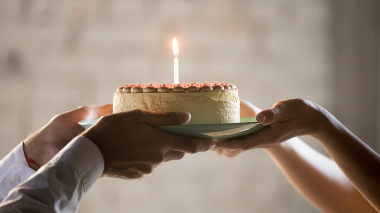 handing birthday cake with candle