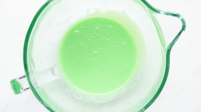 Green colored condensed milk mixture in mixing bowl