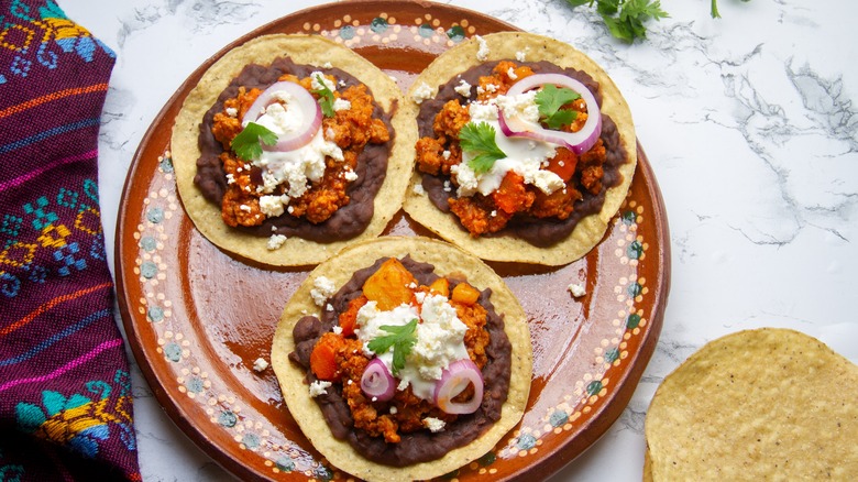 Three tostadas on a decorative plate