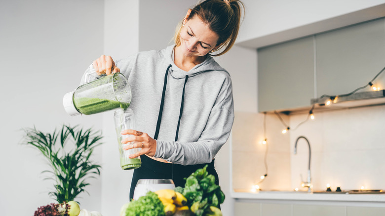 woman pouring green smoothie