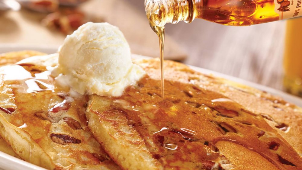 pecan pancakes with butter and maple syrup being poured over top